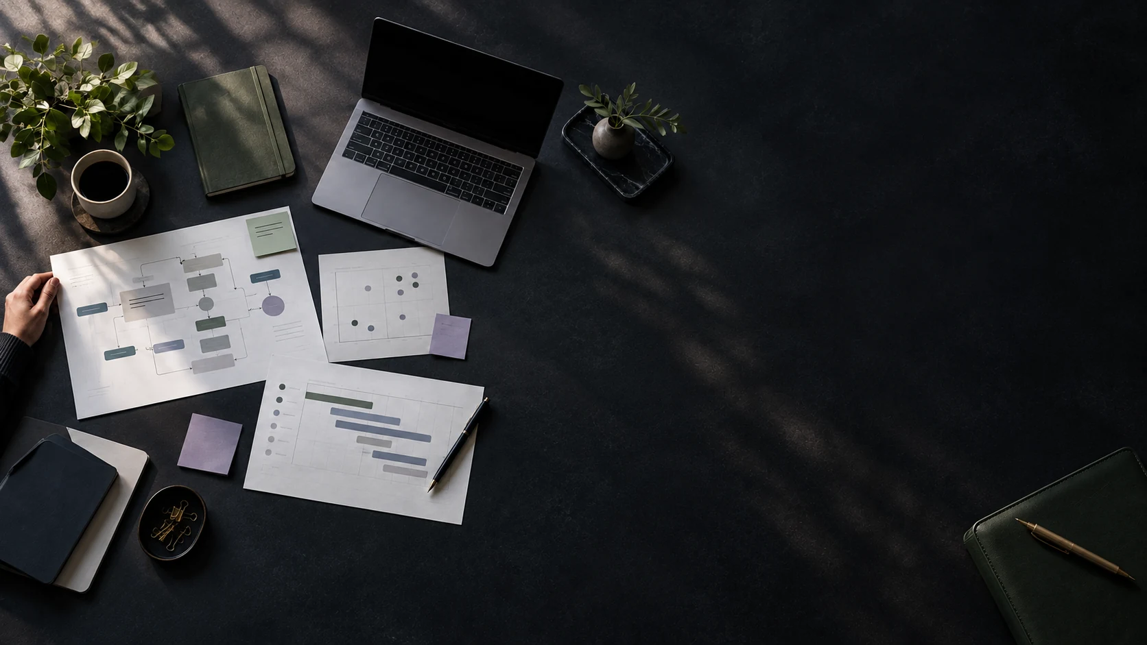An overhead workspace with workflow maps, assessment charts and a laptop arranged for reviewing operational opportunities.
